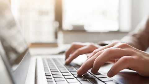 An adult with ADHD typing on her computer as a copyeditor for a news organization.