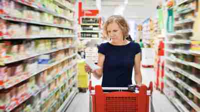 A woman grocery shopping, looking at her meal planning schedule for the week ahead