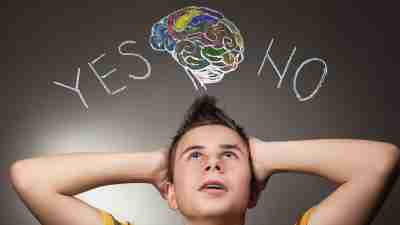A teenager with his hands to his head looking up at the words "yes" and "no" , deciding whether to tells others about his ADHD