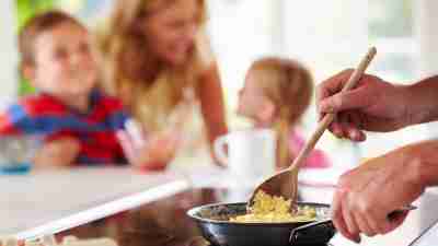 Father preparing scrambled egg breakfast for ADHD children