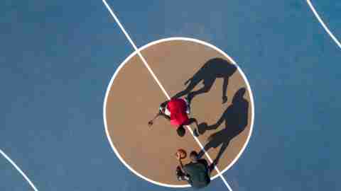 Aerial view of players on a blue and brown basketball court