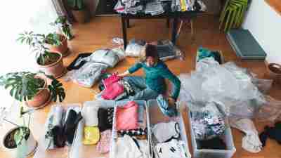 a woman organizes clothes in living room of her home.