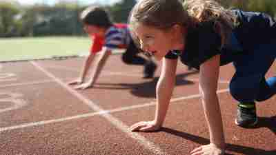 Young girl and boy ready to race on an athletics track