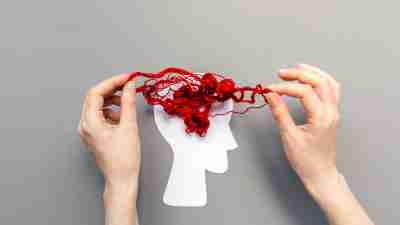 Female's hands unravel the tangled red threads on the silhouette of the head, representing the brain.