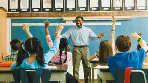 Teacher Standing in Front of a Class of Raised Hands