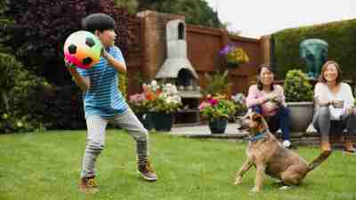 boy with ADHD playing with his dog and a soccer ball in his yard, having a successful summer