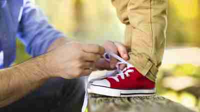 Father teaching son with ADHD to tie shoe laces