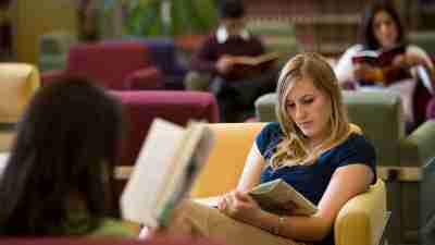 Student with ADHD reading in library preparing to apply for scholarships