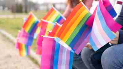 Pride flags held by hands of people sitting in a row.
