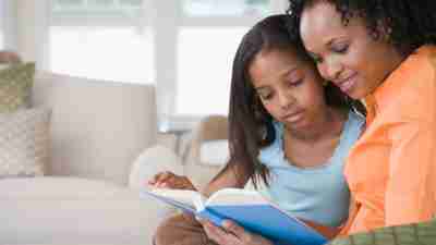 Mother helping her daughter with ADHD work on reading comprehension in their living room