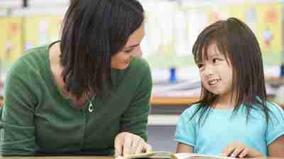 Teacher assisting little girl with ADHD at school