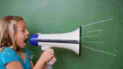 A young girl with ADHD yelling and acting impulsive in class, using a megaphone