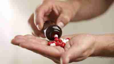 Person with ADHD and addiction problems empties bottle of medication into hand